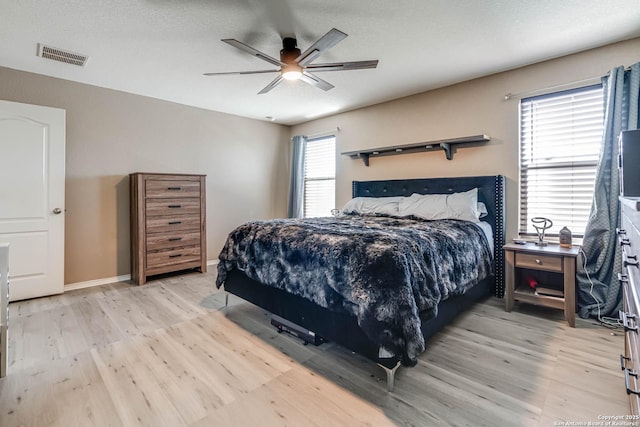 bedroom with ceiling fan, multiple windows, and light hardwood / wood-style flooring