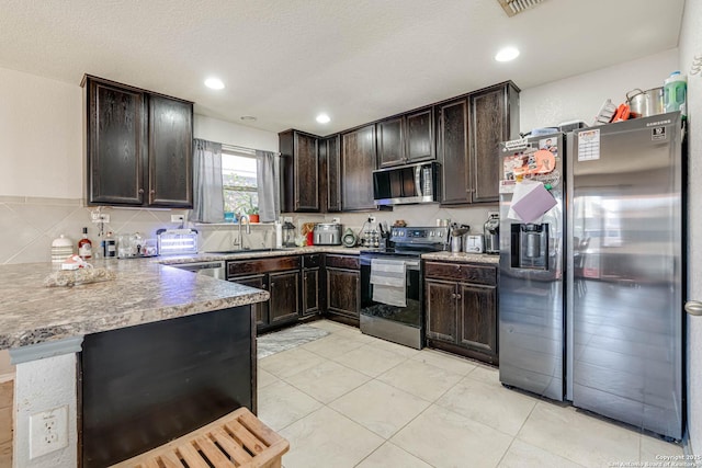 kitchen with sink, dark brown cabinetry, light tile patterned floors, kitchen peninsula, and stainless steel appliances