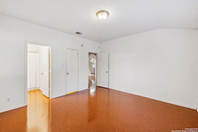 unfurnished bedroom with connected bathroom and lofted ceiling