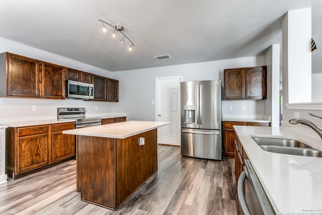 kitchen with a center island, sink, light wood-type flooring, and stainless steel appliances