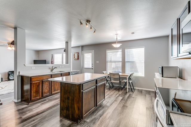 kitchen with ceiling fan, sink, decorative light fixtures, hardwood / wood-style floors, and a center island