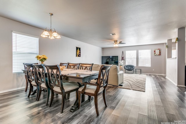 dining room with ceiling fan with notable chandelier and dark hardwood / wood-style floors