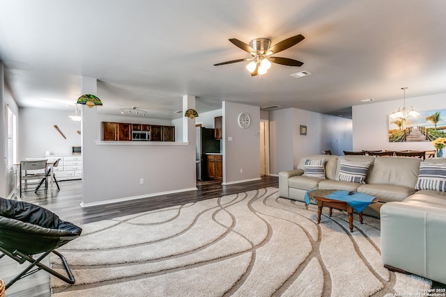 living room with hardwood / wood-style floors and ceiling fan with notable chandelier