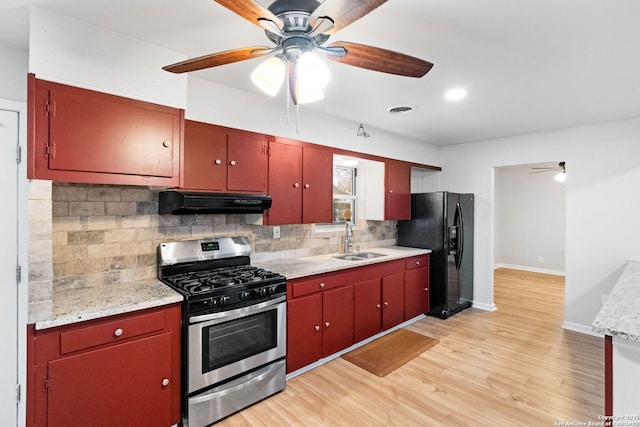 kitchen featuring black fridge, sink, light hardwood / wood-style flooring, gas range, and decorative backsplash