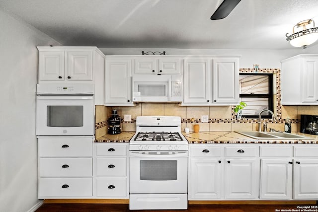 kitchen featuring sink, light stone counters, white appliances, decorative backsplash, and white cabinets