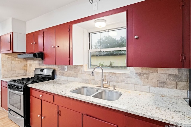 kitchen featuring stainless steel gas stove, backsplash, light hardwood / wood-style flooring, and sink