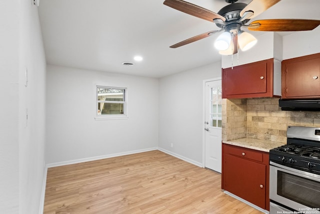 kitchen with backsplash, ceiling fan, exhaust hood, light hardwood / wood-style flooring, and stainless steel range with gas cooktop