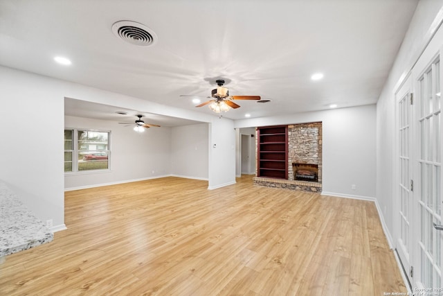 unfurnished living room featuring french doors, light wood-type flooring, and a stone fireplace