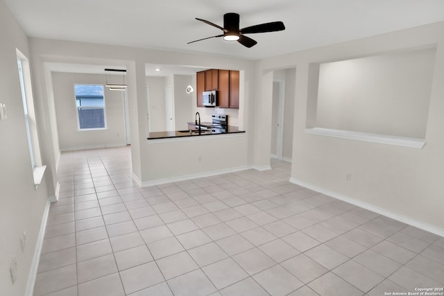 kitchen featuring ceiling fan, sink, light tile patterned floors, hanging light fixtures, and stainless steel range with electric cooktop