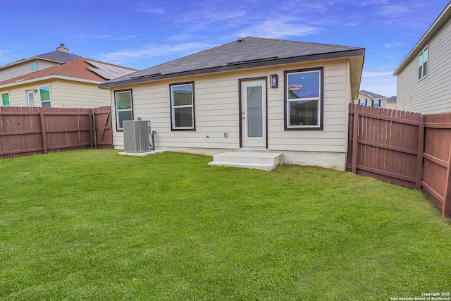 back of property with central air condition unit and a yard