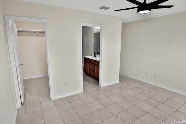 unfurnished bedroom featuring connected bathroom, ceiling fan, a spacious closet, a closet, and light tile patterned flooring