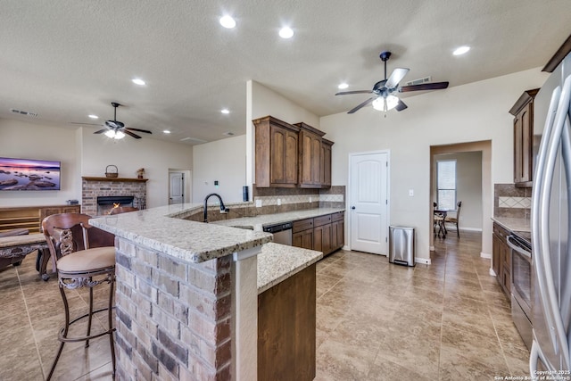 kitchen with kitchen peninsula, a textured ceiling, stainless steel appliances, a breakfast bar, and tasteful backsplash