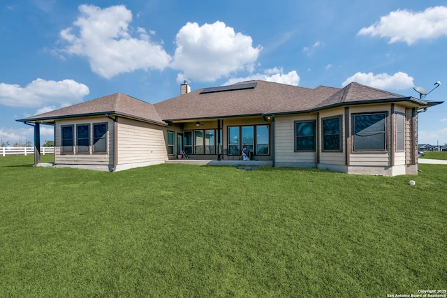 back of property featuring solar panels and a lawn