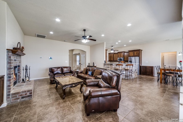 living room featuring a brick fireplace and ceiling fan