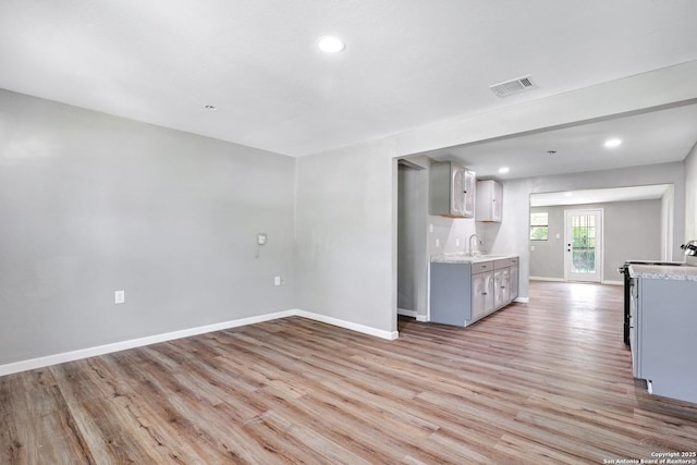 kitchen featuring range, light wood-type flooring, light stone counters, and gray cabinetry