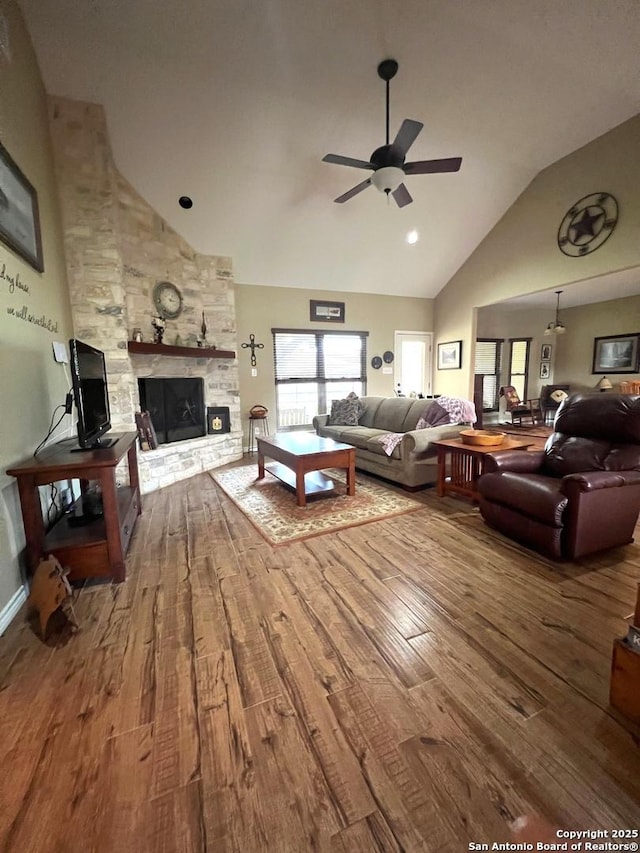 living room with ceiling fan, a fireplace, lofted ceiling, and hardwood / wood-style flooring