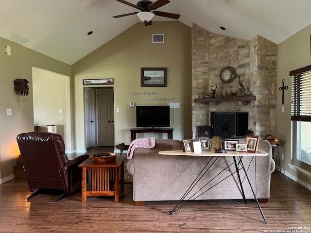 living room featuring hardwood / wood-style flooring, a stone fireplace, ceiling fan, and lofted ceiling