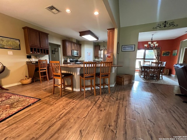 kitchen featuring hardwood / wood-style floors, pendant lighting, stainless steel appliances, and an inviting chandelier