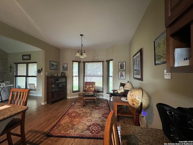 living area featuring plenty of natural light, wood-type flooring, and an inviting chandelier