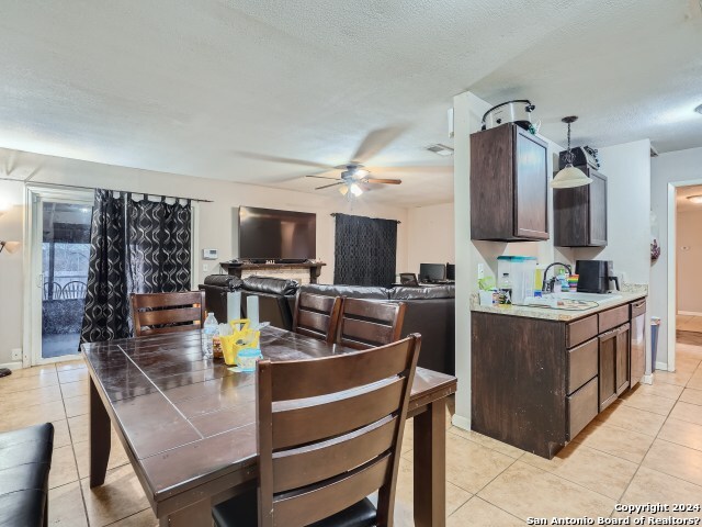 dining space featuring light tile patterned floors, a textured ceiling, ceiling fan, and sink