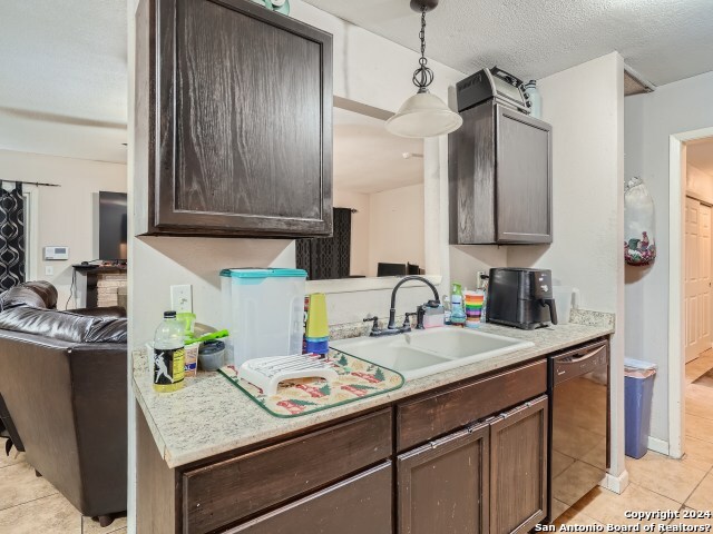 kitchen with pendant lighting, dishwasher, dark brown cabinetry, and sink