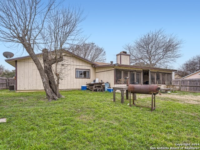 rear view of house featuring a yard and a sunroom