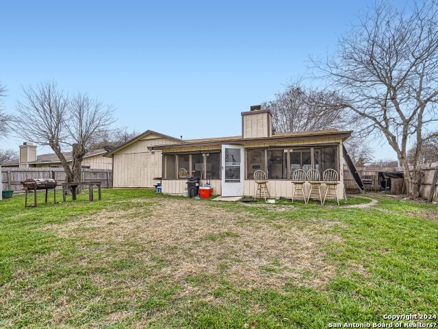 rear view of house featuring a sunroom and a yard