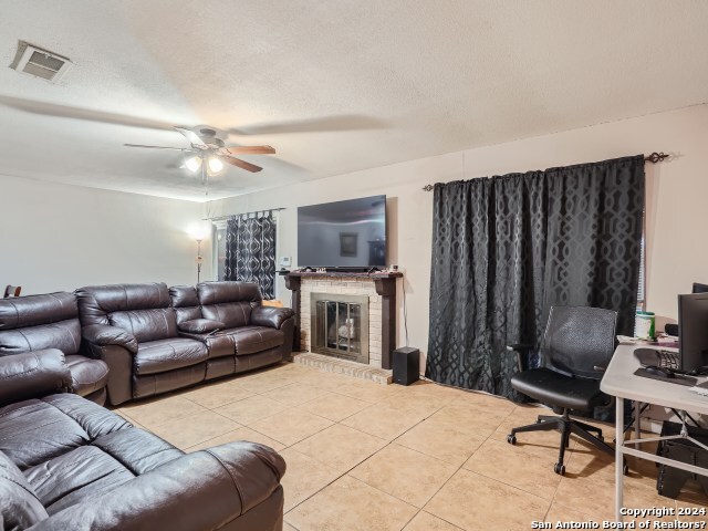 living room with light tile patterned floors, a textured ceiling, and ceiling fan