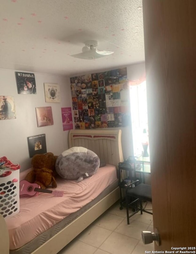 bedroom with a textured ceiling, ceiling fan, and light tile patterned flooring