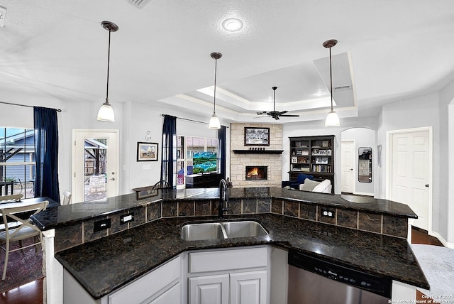 kitchen featuring white cabinetry, dishwasher, sink, a raised ceiling, and decorative light fixtures