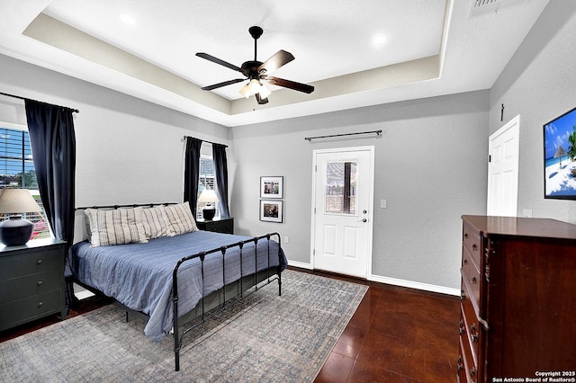 bedroom with ceiling fan and a raised ceiling