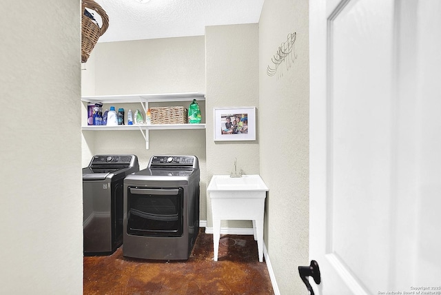 laundry room with a textured ceiling, washer and clothes dryer, and sink