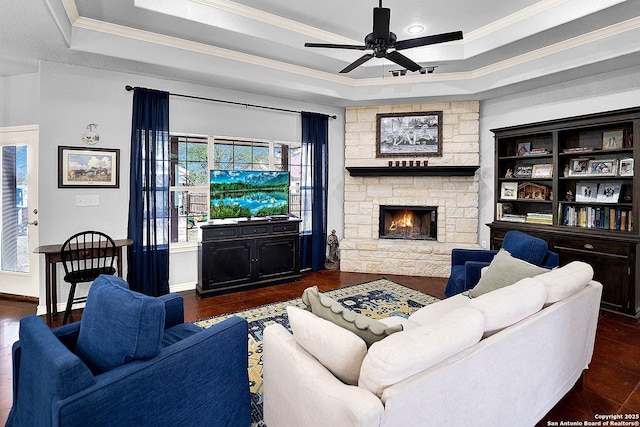 living room with a tray ceiling, dark hardwood / wood-style flooring, a fireplace, and ornamental molding