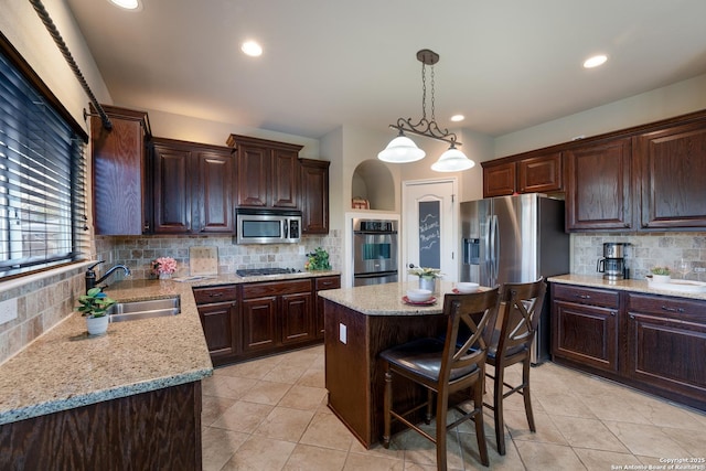 kitchen with sink, a center island, hanging light fixtures, backsplash, and appliances with stainless steel finishes