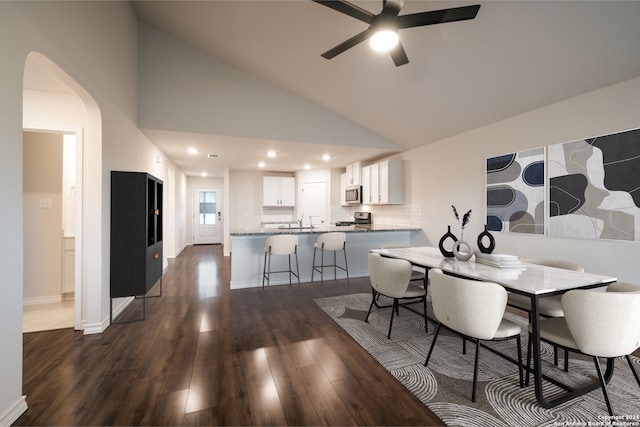 dining room with high vaulted ceiling, ceiling fan, dark wood-type flooring, and sink