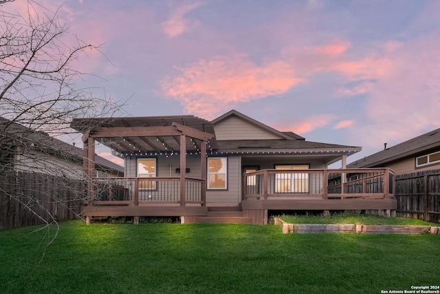 back house at dusk with a pergola, a deck, and a lawn