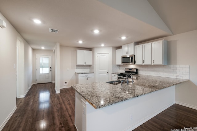 kitchen with lofted ceiling, white cabinets, sink, appliances with stainless steel finishes, and kitchen peninsula