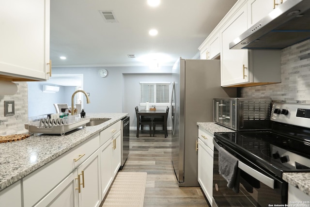 kitchen with backsplash, sink, light stone countertops, white cabinetry, and stainless steel appliances