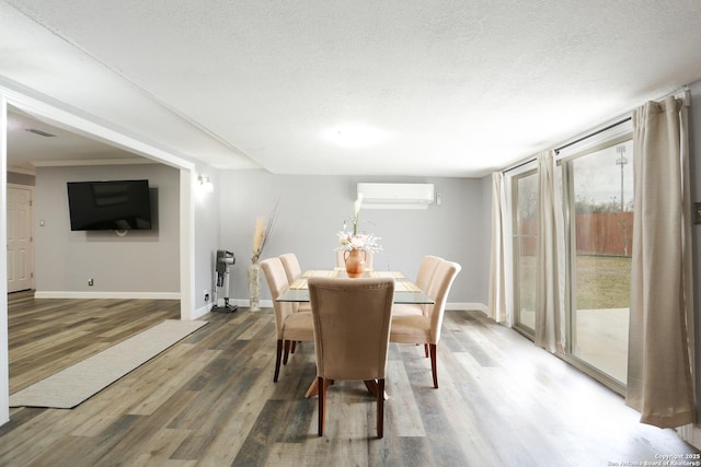 dining area with a textured ceiling, dark hardwood / wood-style flooring, and a wall mounted air conditioner