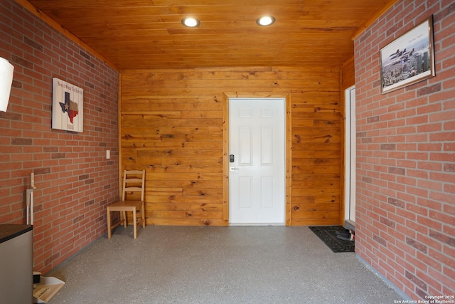 interior space with wood walls, wooden ceiling, and brick wall