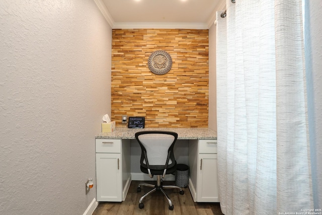 office area with light wood-type flooring, built in desk, and crown molding