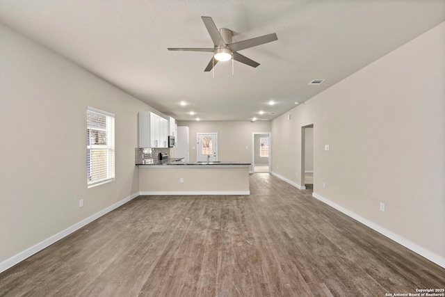 unfurnished living room featuring ceiling fan, sink, and dark wood-type flooring