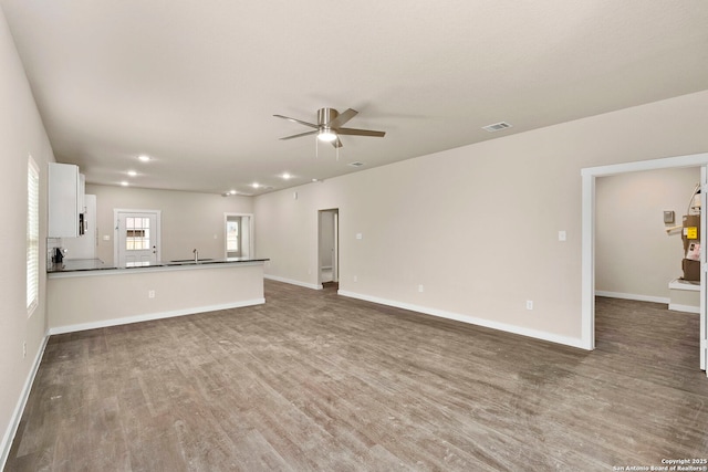 unfurnished living room featuring ceiling fan, sink, and hardwood / wood-style floors