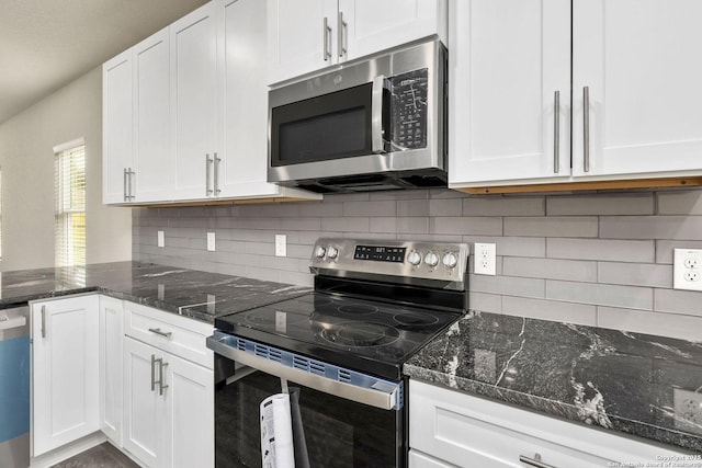 kitchen featuring decorative backsplash, white cabinets, dark stone counters, and appliances with stainless steel finishes