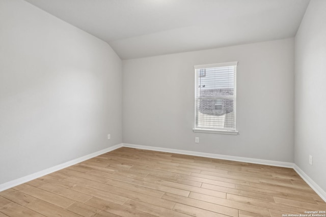 unfurnished room featuring light hardwood / wood-style floors and lofted ceiling