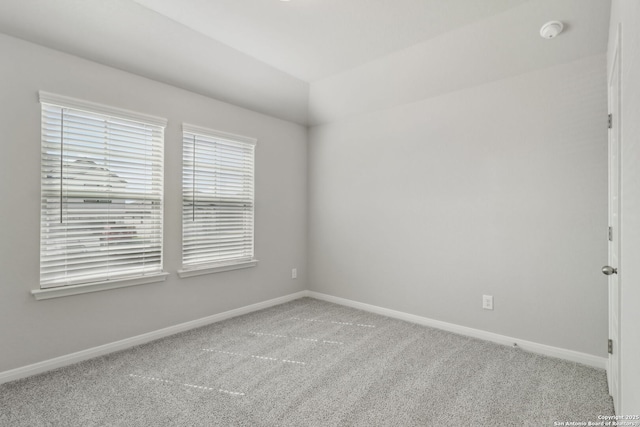 carpeted empty room featuring vaulted ceiling