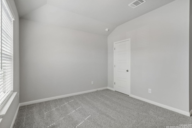 carpeted empty room featuring a wealth of natural light and vaulted ceiling