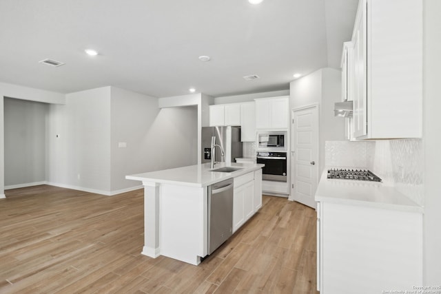 kitchen with white cabinets, an island with sink, appliances with stainless steel finishes, and tasteful backsplash