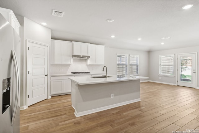 kitchen with white cabinets, sink, light wood-type flooring, an island with sink, and stainless steel appliances