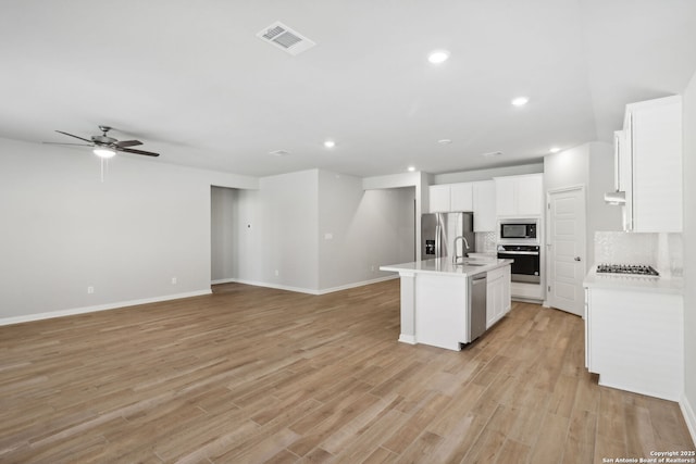 kitchen with a center island with sink, sink, tasteful backsplash, white cabinetry, and stainless steel appliances